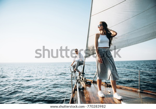 An attractive girl walks on a\
wooden yacht. She swims with her handsome guy on the\
sea