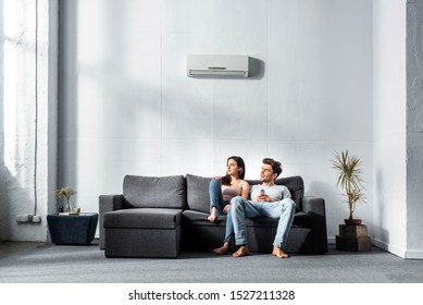 attractive girlfriend and handsome boyfriend sitting on sofa in apartment 