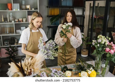 Attractive girls working as florists. Arranging flowers into bouquets and sharing advice with each other. Selling floral gifts in the flower shop. - Powered by Shutterstock