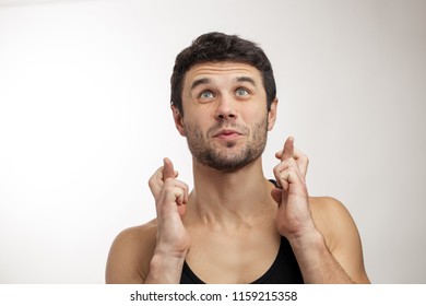 Attractive Guy With Crossed Fingers Looking Up. Please, God, Help Me. Copy Space. Isolated White Background