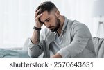 Attractive guy feeling desperately, sad, looking worried depressed thoughtful and lonely suffering depression on couch at home in middle age crisis, mental health personal problems and lifestyle