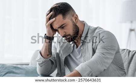 Attractive guy feeling desperately, sad, looking worried depressed thoughtful and lonely suffering depression on couch at home in middle age crisis, mental health personal problems and lifestyle
