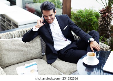 Attractive and handsome businessman using mobile phone, asian businessman having a phone talk, wealthy man talking on the smart phone seated in the terrace of modern lounge cafe at his work break - Powered by Shutterstock