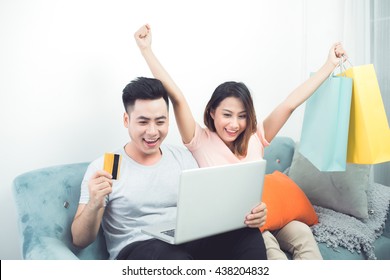 Attractive Happy Asian Couple Using Laptop Shopping Online Using Credit Card.