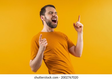 Attractive happy bearded football fan cheering for his favorite team celebrating victory. Lucky gambler placing bets at bookmakers website wining money. Isolated on yellow background. - Shutterstock ID 2002767020