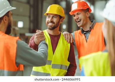 Attractive, happy, bearded, middle aged man wearing protective helmet shaking hands with colleagues standing in warehouse, greetings, deal. Concept of cooperation, communication - Powered by Shutterstock