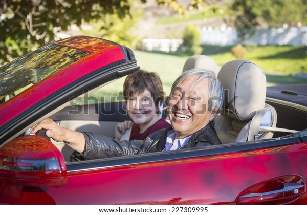 Attractive Happy Chinese Couple Enjoying An\
Afternoon Drive in Their\
Convertible.
