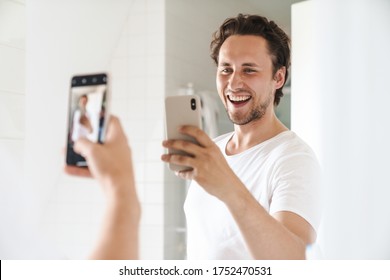 Attractive Happy Confident Young Man Standing In Front Of The Bathroom Mirror, Taking A Selfie