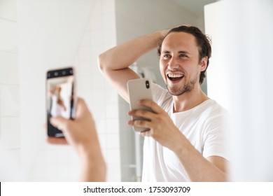 Attractive Happy Confident Young Man Standing In Front Of The Bathroom Mirror, Taking A Selfie