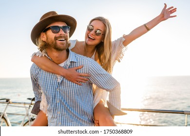 attractive happy couple laughing traveling in summer by sea, man and woman wearing sunglasses, boho hipster style fashion having fun together