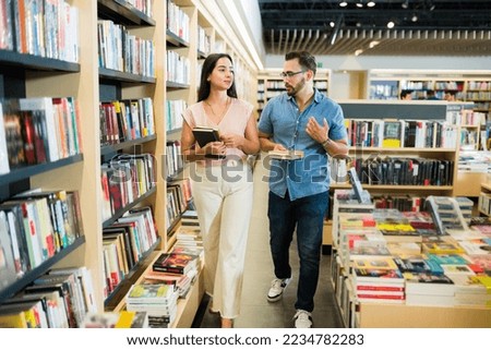 Attractive happy couple walking and talking at the bookstore while buying books together