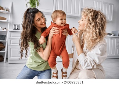 attractive happy lgbt couple playing actively with their pretty toddler daughter, modern parenting - Powered by Shutterstock