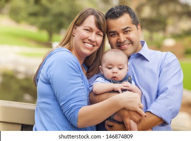 Attractive Happy Mixed Race Young Family Posing For A Portrait Outside In The Park.