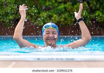 Attractive happy senior person, a 69-year-old woman who loves pool activities smiles playing with water. With cap and goggles. - Shutterstock ID 1539011174
