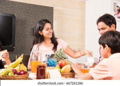 An Attractive Happy, Smiling Asian Indian Family Of Mother, Father, Son And Daughter Eating Healthy Food & Salad At A Dining Table. Indians Eating Breakfast, Lunch Or Dinner. Selective Focus