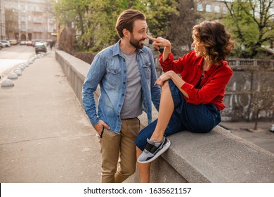 attractive happy smiling man and woman in hipster casual outfit traveling together in Europe, stylish couple in love flirting sitting in street on romantic trip, sunny autumn city, having fun romance