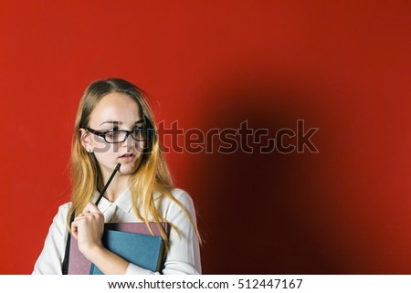 attractive happy smiling student blonde girl in white shirt with books on red background, student concept