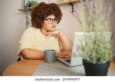 Attractive happy stylish plus size African black woman student afro hair in glasses studying online working on laptop computer at home office workspace. Diversity. Remote work, distance education - Shutterstock ID 1974993977