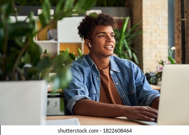 Attractive Happy Young Man Student Studying At The Cafe, Sitting At The Desk, Using Laptop Computer. Man Looking Out The Window With Interest