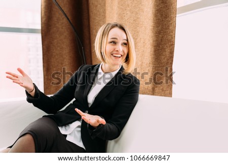Attractive happy young women wearing skirts sitting in armchairs in reception area