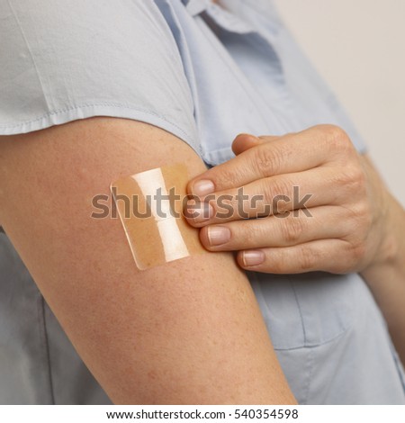 ATTRACTIVE HEALTHY YOUNG BLONDE WOMAN APPLYING TRANSPARENT NICOTINE PATCH TO ARM