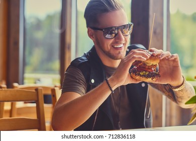 Attractive Hipster Dressed In Leather Jacket Eating A Vegan Burger.