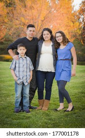 Attractive Hispanic Family Portrait In A Colorful Fall Outdoor Setting At The Park.