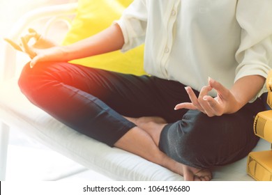 Attractive Hold Hand Of Beautiful Woman Meditates On Long White Chair With Stack Of Colored Books Left Beside Her In Living Room.Businesswoman Practicing Yoga At Home.Relax After Work Concept