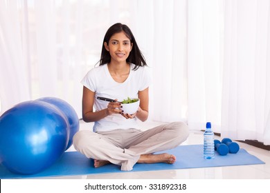 Attractive Indian Woman Eating Healthy Salad On Yoga Mat