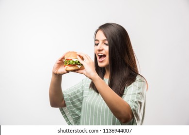 Attractive Indian/Asian Girl Eating Burger On White Or Yellow Background
