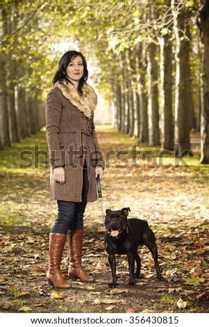 Attractive lady and her dog enjoying their time in autumn alley
