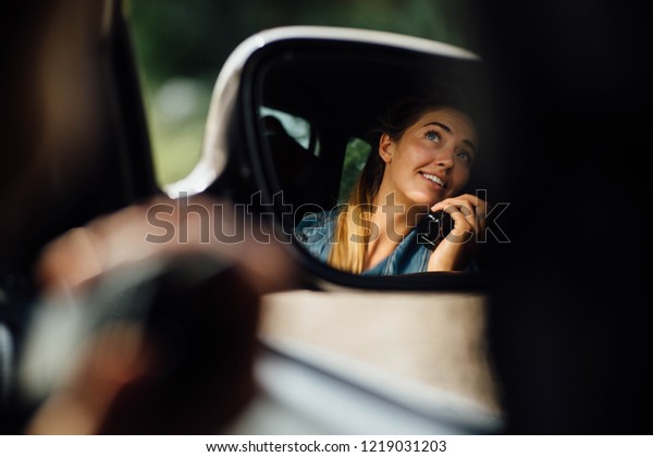 Attractive lady riding in the car, talking on the\
radio. Fast speed, car racing. Extreme sport. Smiling girl in the\
mirror.