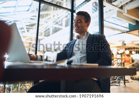 Attractive Latin American young dark-haired male engineer with a pleased smile working in his office