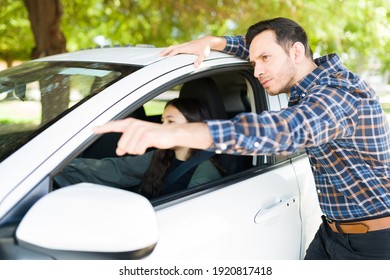 Attractive Latin Man Giving Directions To Her Teen Daughter. Teenage Girl Sitting On The Driver's Seat Of The Car And Listening To Her Dad Before Start Driving