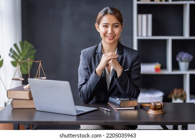 Attractive Lawyer In Office Business Woman And Lawyers Discussing Contract Papers With Brass Scale On Wooden Desk In Workplace. Law, Legal Services, Advice, Justice And Real Estate Concept.