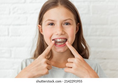 Attractive little girl shows index fingers myofunctional trainer. Help equalize the growing teeth and correct bite, develop mouth breathing habit. Corrects the position of the tongue - Shutterstock ID 2142291955