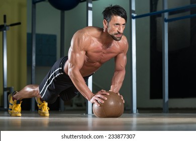 Attractive Male Athlete Performing Push-Ups On Medicine Ball - Powered by Shutterstock