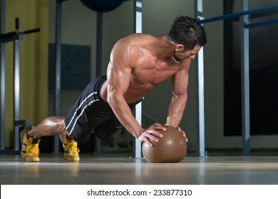 Attractive Male Athlete Performing Push-Ups On Medicine Ball - Powered by Shutterstock