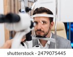 Attractive male doctor ophthalmologist is checking the eye vision of handsome middle age man in modern clinic. Doctor and patient during medical check up in ophthalmology clinic. 