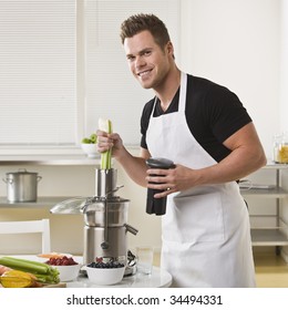 Attractive Male With Juicer, Holding Celery And Smiling At Camera. Square.