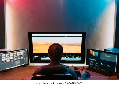 Attractive Male Video Editor Works with Footage or Video on His Personal Computer, he Works in Creative Office Studio or home. Neon lights - Shutterstock ID 1946952241