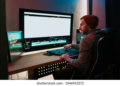 Attractive Male Video Editor Works with Footage or Video on His Personal Computer, he Works in Creative Office Studio or home. Neon lights