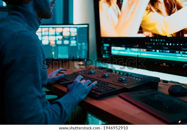 Attractive Male Video Editor Works with Footage or\
Video on His Personal Computer, he Works in Creative Office Studio\
or home. Neon lights