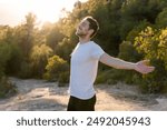 An attractive man breathes fresh air from nature at sunset. Healthy lifestyle and emotional well-being