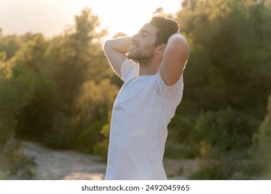 An attractive man breathes fresh air from nature at sunset. Healthy lifestyle and emotional well-being - Powered by Shutterstock