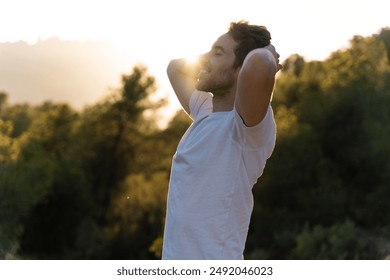 An attractive man breathes fresh air from nature at sunset. Healthy lifestyle and emotional well-being - Powered by Shutterstock