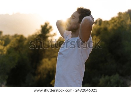 An attractive man breathes fresh air from nature at sunset. Healthy lifestyle and emotional well-being