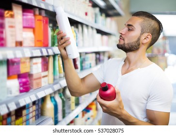 Attractive Man Buying Shampoo In Shopping Mall