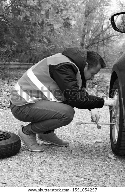 attractive man changing\
broken wheel on car