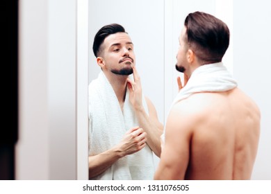Attractive Man Checking Himself in the Mirror. Attractive guy getting ready following beauty care routine
